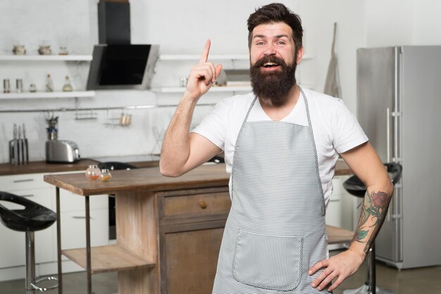 Vous avez une nouvelle idée de sa recette Heureux cuisinier gardant le doigt levé dans la cuisine Chef barbu suivant la recette pour impressionner Cuisiner un dîner avec une recette traditionnelle Préparer un repas avec une recette de cuisine