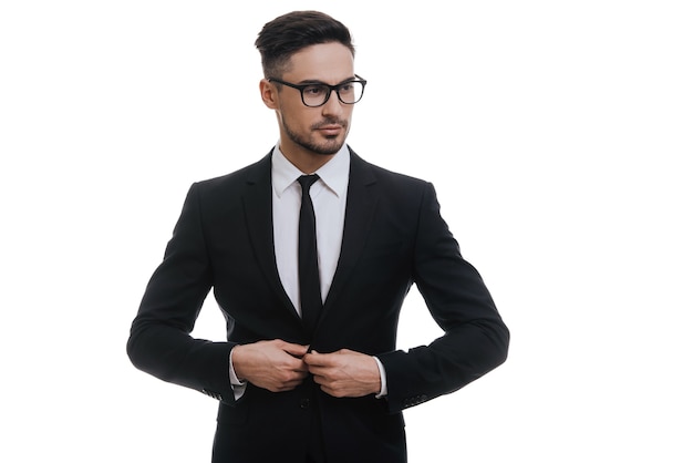 Vous cherchez juste parfait. Beau jeune homme en costume complet boutonnant sa veste et détournant les yeux