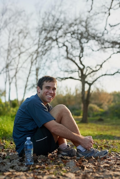 Vous devez vous assurer que vos lacets sont attachés Portrait en pied d'un bel athlète masculin attachant ses lacets lors d'une randonnée dans la forêt