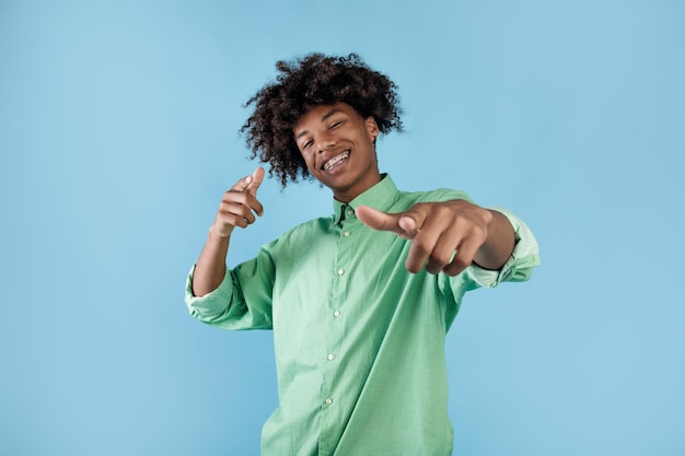 Vous êtes le suivant Joyeux mec afro-américain pointant du doigt la caméra et souriant vous choisissant sur fond bleu