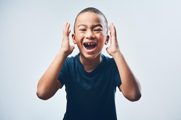 Vous les gars devinez quoi Prise de vue en studio d'un mignon petit garçon qui a l'air étonné sur un fond gris