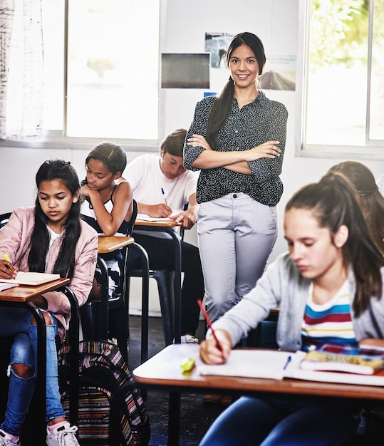 Vous pouvez me faire confiance avec l'éducation de votre enfant Portrait d'une jolie jeune enseignante debout les bras croisés dans une salle de classe