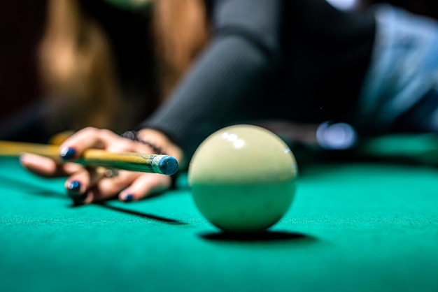 Vous pouvez voir des mains tenir habilement une queue et essayer d'enfoncer une couche de billard dans le trou