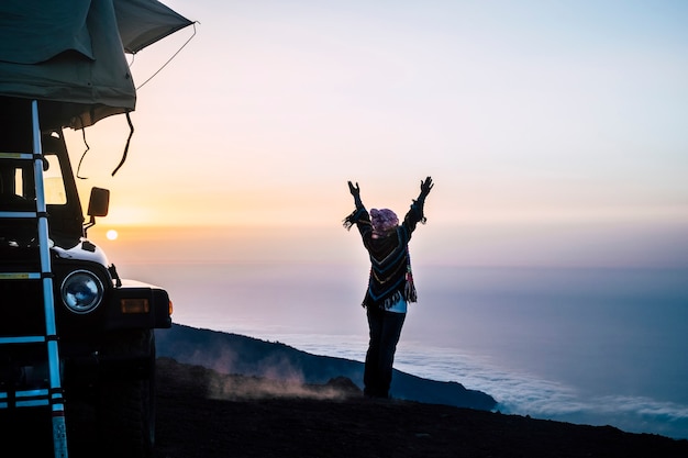 Voyage et activité de loisirs de plein air sauvage avec une femme heureuse devant les nuages et les montagnes au coucher du soleil