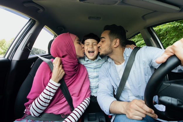 Voyage automatique. Joyeuse famille musulmane avec petit fils en voiture ensemble