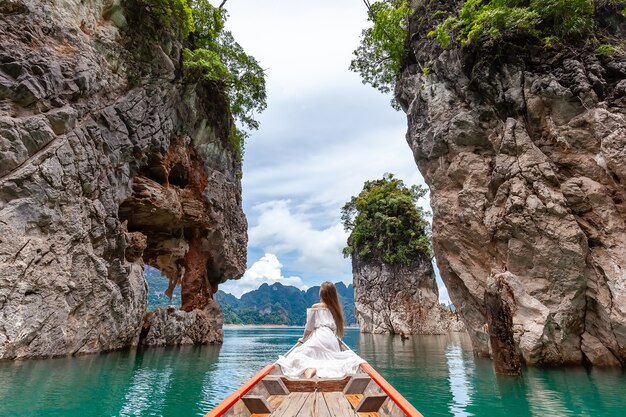 Voyage femme assise sur un bateau près de trois rochers célèbres dans le parc de Khao Sok, Thaïlande