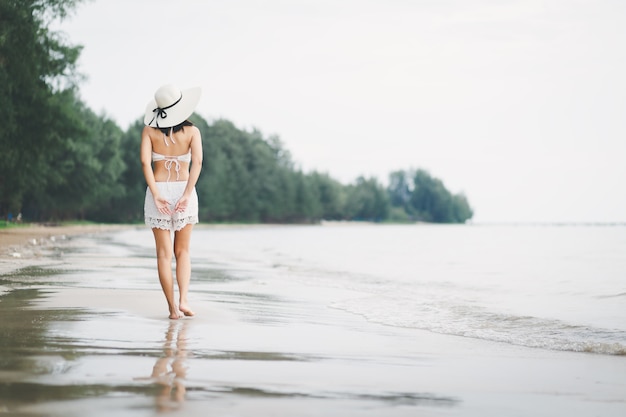 Voyage femme marchant sur la plage au coucher du soleil