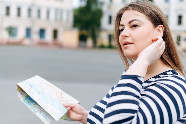 Voyage femme visitant la ville avec la carte dans ses mains et regardant autour.