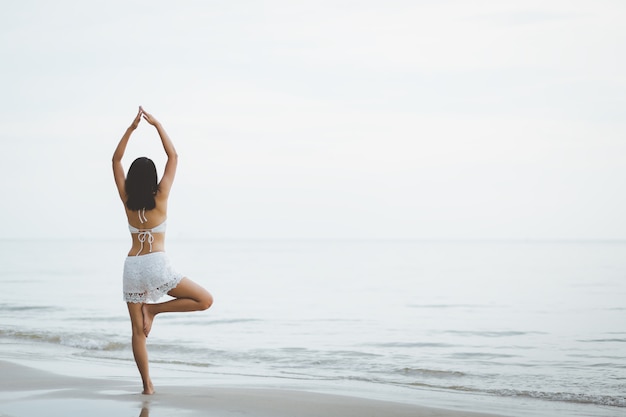 Voyage femme yoga sur la plage