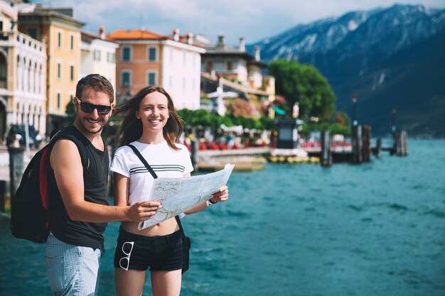 Voyage Italie Europe Couple souriant amoureux d'une carte au lac de Garde avec lac de montagnes et ville