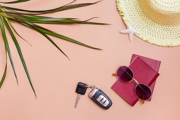 Voyage lumineux d'été à plat avec des lunettes de soleil, des passeports, des clés de voiture et un chapeau de paille sur fond beige. Voyage en voiture. Vue de dessus