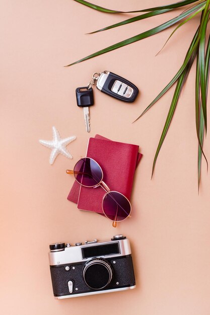 Voyage lumineux à plat avec lunettes de soleil, passeports, appareil photo vintage et clés de voiture sur fond beige. Voyage en voiture. Vue de dessus et verticale