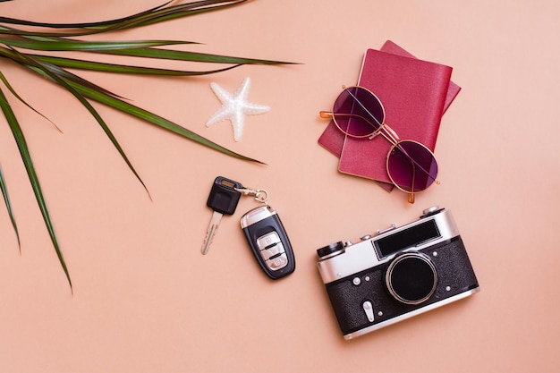 Photo voyage lumineux à plat avec lunettes de soleil, passeports, appareil photo vintage et clés de voiture sur fond beige. voyage en voiture. vue de dessus