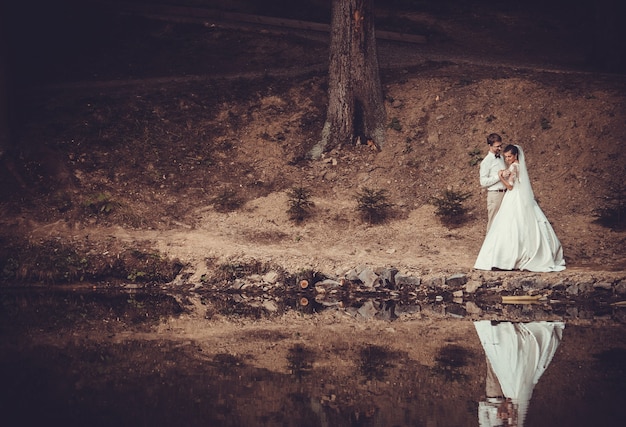 Voyage de noces. Les mariés s'embrassant sur la rive du lac.