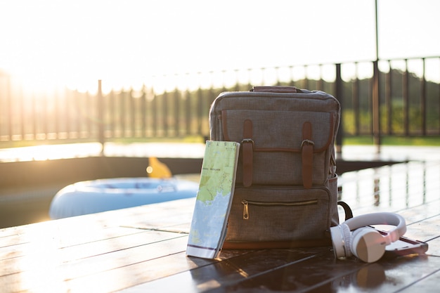 Voyage avec sac à dos avec casque carte appareil photo écouteur et téléphone intelligent sur la piscine dans la villa avec piscine