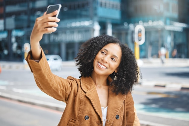 Voyage selfie et femme noire dans une ville heureuse et sourire en vacances sur fond urbain