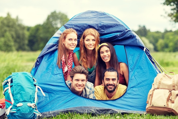 voyage, tourisme, randonnée, équipement et concept de personnes - groupe d'amis heureux avec des sacs à dos en tente au camping