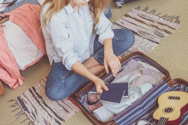 Voyage et vacances d'été. Jeune femme, emballage, valise, chez soi