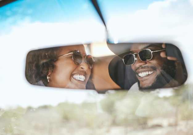 Voyage en voiture et couple noir heureux de passer des vacances dans un miroir de voiture reflétant ensemble Bonheur et sourire d'amour d'une petite amie et d'un petit ami lors d'un voyage de vacances prêt pour la conduite d'été