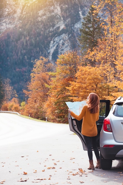 Voyage en voiture. Road trip - une touriste avec une carte se tient près de la voiture. L'Autriche