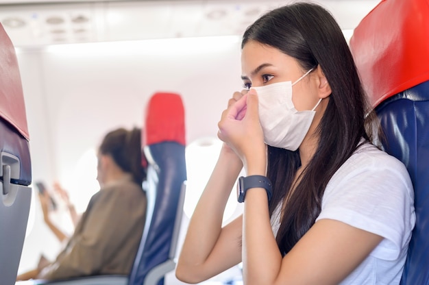 Voyager femme portant un masque de protection à bord de l'avion