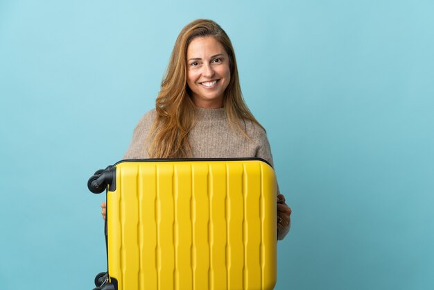 Voyageur d'âge moyen femme tenant une valise isolée en vacances avec valise de voyage