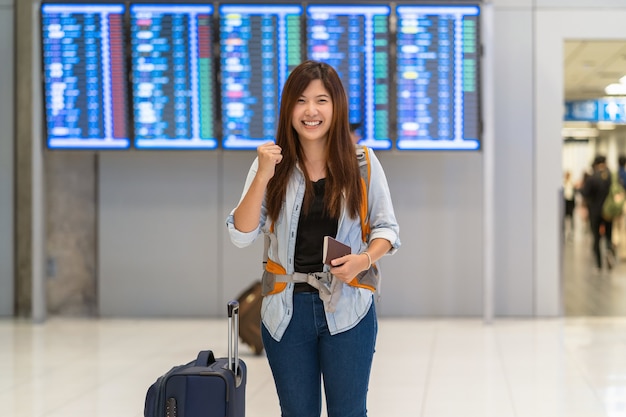 Voyageur asiatique avec bagages et passeport marchant sur le tableau de bord pour l&#39;enregistrement