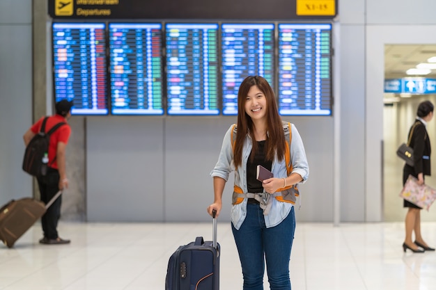 Voyageur asiatique avec des bagages avec passeport sur la planche de vol