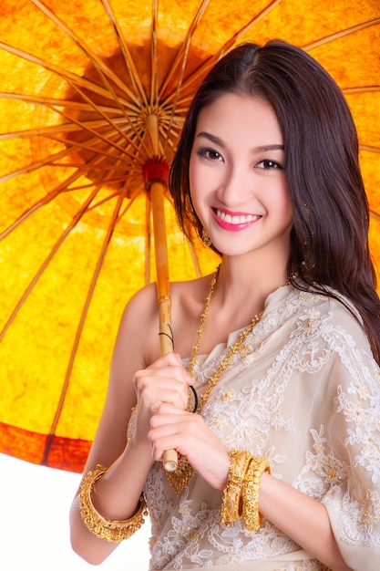 Photo voyageur asiatique dans une ancienne robe thaïlandaise avec un sourire sur un fond blanc isolé