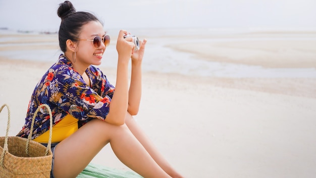 Voyageur asiatique femme asseoir et se détendre sur la plage au bord de la mer