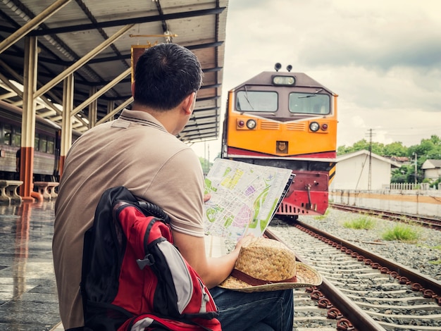 Voyageur assis et regardant la carte dans la gare. Concept de voyage