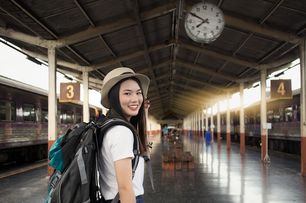 Photo voyageur belle jeune femme regardant la caméra et sourire à une gare