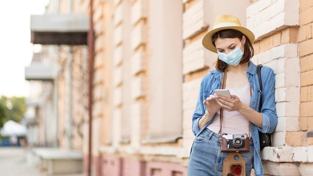 Voyageur avec chapeau et masque facial parcourant le téléphone mobile