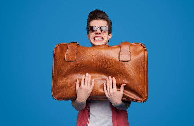 Photo voyageur comique avec valise lourde en studio