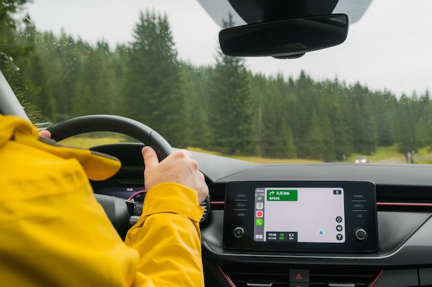 Un voyageur conduit une voiture à travers un col parmi la forêt de montagne