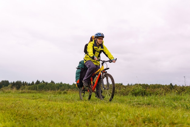 Un voyageur cycliste masculin avec un sac à dos et un sac à dos se promène à travers le paysage naturel