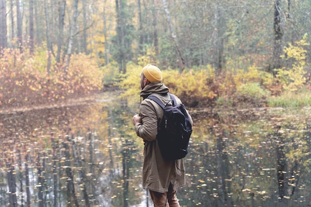Voyageur dans les bois un homme avec un sac à dos se promène et voyage sur une piste dans une belle forêt d'automne...