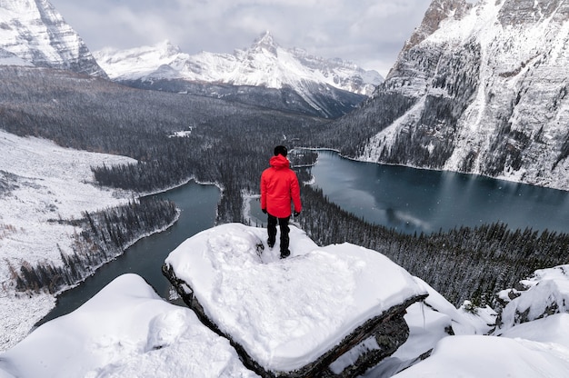 Voyageur debout sur un rocher sur le plateau d'Opabin avec le lac O'hara dans la neige au parc national Yoho, Canada