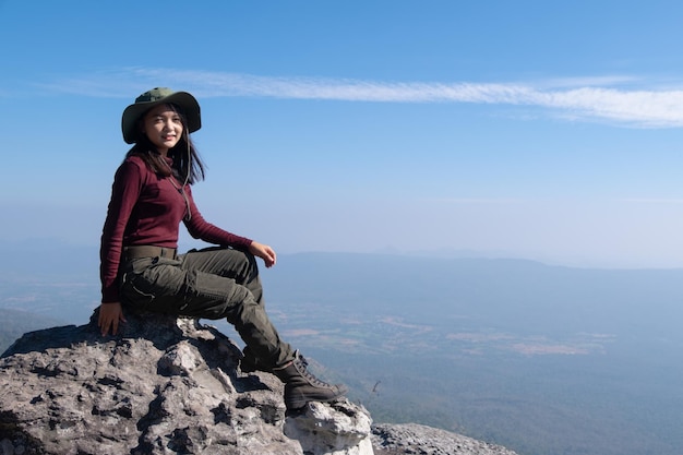 Un voyageur est assis sur un rocher sur une haute montagne avec une belle vue sur le ciel