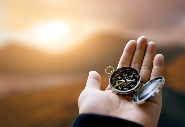 Voyageur explorateur homme tenant une boussole dans une main dans les montagnes au point de vue du lever du soleil