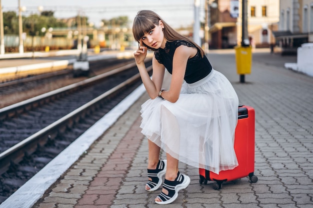 Voyageur femelle avec valise rouge train en attente sur la gare