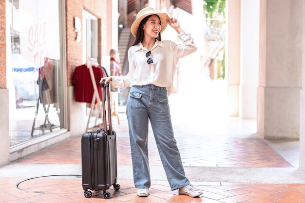 Voyageur femme faisant glisser le sac de bagages valise noire à pied à l'embarquement des passagers à l'aéroport