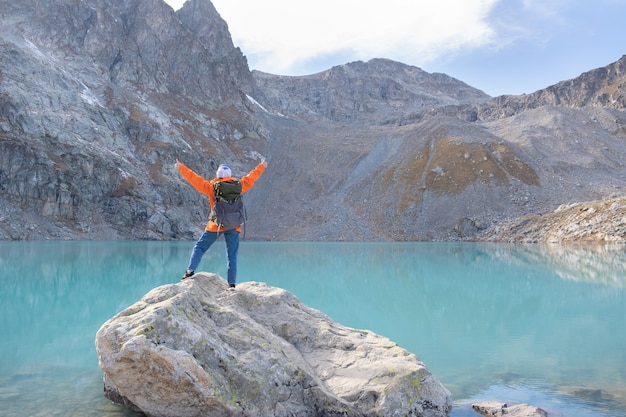 Voyageur de femme avec un sac à dos lourd sur une montagne de falaise au-dessus d'aventure de style de vie de voyage de lac