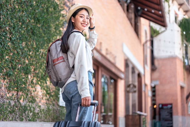 Voyageur de femme souriante faisant glisser le sac de bagages valise noire marchant à l'embarquement des passagers à l'aéroport, concept de voyage.