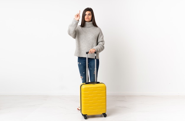 Voyageur femme avec une valise sur un mur blanc touchant sur écran transparent