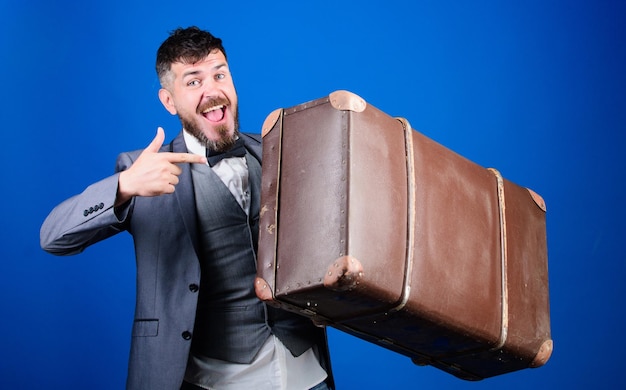 Voyageur hipster avec bagages Assurance bagages Homme hipster barbu bien soigné avec grosse valise Emportez toutes vos affaires avec vous Valise lourde Service de livraison Concept de voyage et de bagages