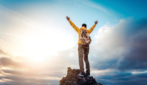 Voyageur d'homme au sommet de la montagne profitant d'une vue sur la nature avec les mains levées au-dessus des nuages