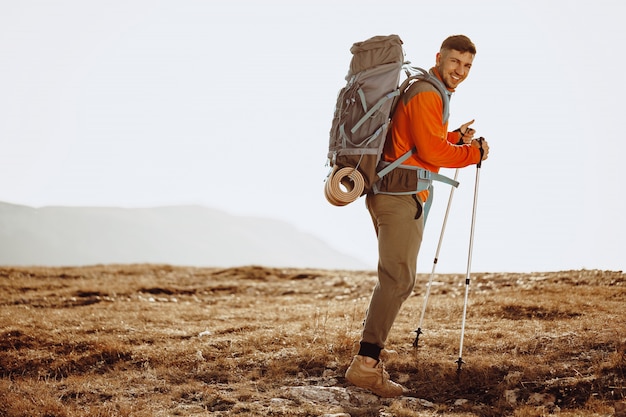 Voyageur de l'homme avec des bâtons de randonnée qui monte la montagne