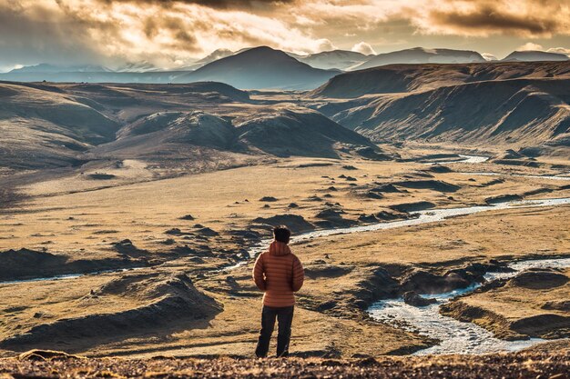 Voyageur homme debout sur la montagne volcanique et ciel coucher de soleil dans les hautes terres islandaises en été en Islande