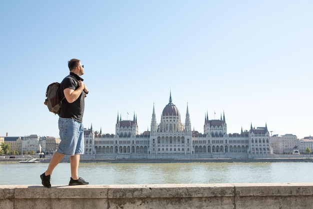 Voyageur d'homme devant le bâtiment du parlement de Budapest